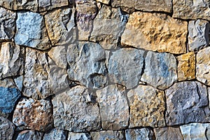 Colorful natural stone wall background with irregular blue and orange stones