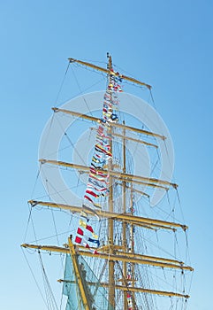 Colorful nautical sailing flags flying in the wind from the lines of a sailboat mast backlit in bright blue sky by the