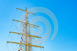Colorful nautical sailing flags flying in the wind from the lines of a sailboat mast backlit in bright blue sky by the