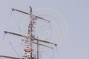 Colorful nautical sailing flags flying in the wind from the lines of a sailboat mast backlit in bright blue sky by the