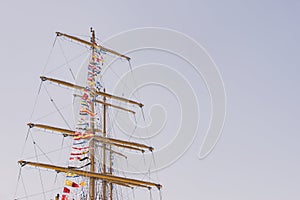 Colorful nautical sailing flags flying in the wind from the lines of a sailboat mast backlit in bright blue sky by the