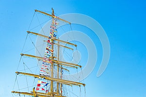 Colorful nautical sailing flags flying in the wind from the lines of a sailboat mast backlit in bright blue sky by the