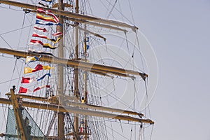 Colorful nautical sailing flags flying in the wind from the lines of a sailboat mast backlit in bright blue sky by the