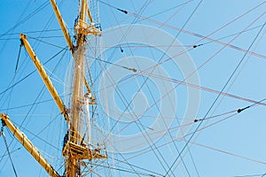 Colorful nautical sailing flags flying in the wind from the lines of a sailboat mast backlit in bright blue sky by the sun