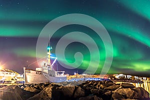 Colorful northern lights Aurora borealis with a boat in the foreground in Iceland