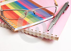 Colorful notebook pen and glasses on white