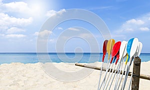 Colorful oars on old bamboo fence with space on sandy beach background