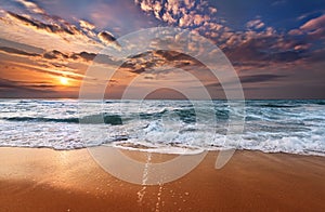 Colorful ocean beach sunrise with deep blue sky.