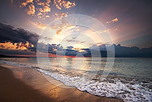 Colorful ocean beach sunrise with deep blue sky and sun rays.