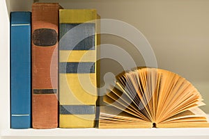 colorful old books on a white wooden book shelf