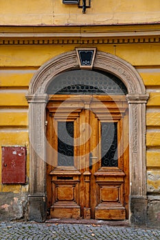 Colorful old elegant front wooden carved entrance yellow door with glass inserts, stone portal with floral ornament, picturesque