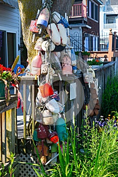 Colorful old fishing floats and buoys hang from a tree near the fisherman's house