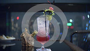 A colorful orange cocktail with ice on the table in the skybar, overlooking the night skyscrapers. background blur. 4k