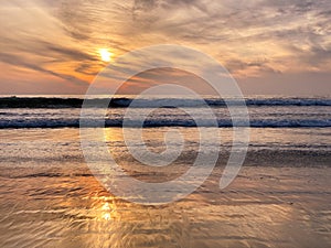 Colorful orange ocean beach sunset with deep clouded sky.