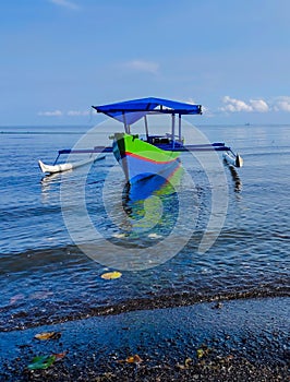Colorful outrigger boat with tranquil scene on shallow beach
