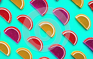 Colorful oval citrus jelly candies pattern on a turquoise background. Yellow, pink, red, orange round shaped marmalade