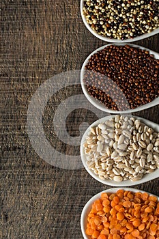 Colorful overhead view of grains in white spoon on wood