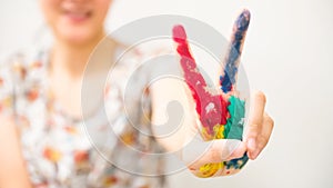 Colorful paint hand with victory gesture of smiling woman