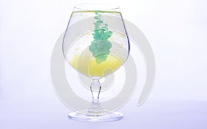Colorful paint in water in a crystal glass on a white background