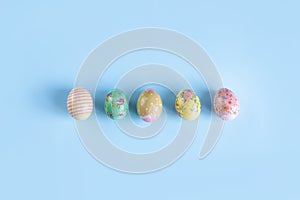 Colorful, painted for Easter, chicken eggs lie in a row on a blue background