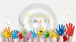 Colorful painted hands in front of a decorated wall with the sentence For our future in German