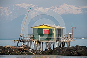 Colorful Palafitte with fishing net over water and rocks, mountains in the background photo