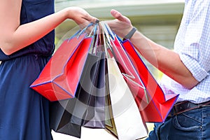 Colorful paper bags in hands of couple. Shopping and sales.