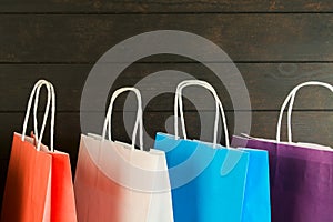 Colorful paper bags on wooden background with copy space