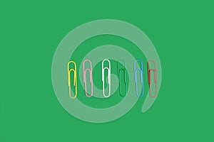 Colorful paper clip on green background.