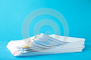 Colorful paper clip with pile of overload white paperwork on blue