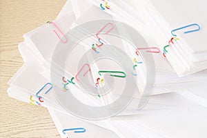 Colorful paper clip with stack of overload paperwork