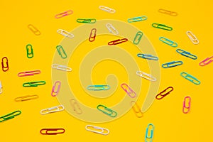 Colorful paper clip on yellow background. Close up top view