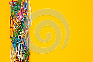 Colorful paper clip on yellow background. Close up top view