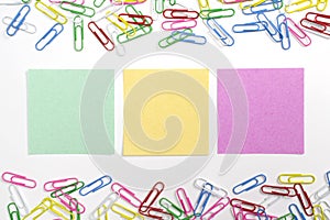 Colorful paper clips and 3 nore papers in the centre isolated on white