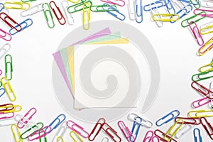 Colorful paper clips and 3 nore papers in the centre isolated on white