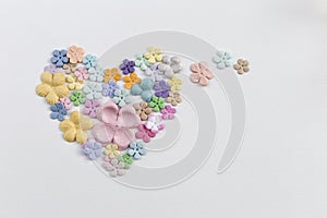 Colorful paper flower arrange in heart shape on white paper texture background