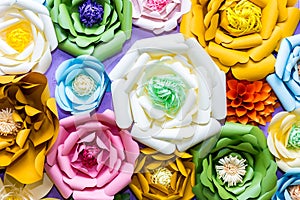 Colorful paper flowers on wall. Handmade artificial floral decoration. Spring abstract beautiful background and texture
