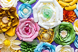 Colorful paper flowers on wall. Handmade artificial floral decoration. Spring abstract beautiful background and texture