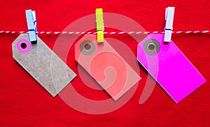 Colorful paper notes and clothespins on a red background. Empty color cardboard price tags, sale tag, gift tag, address label,