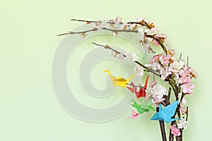 Colorful paper origami birds on flowering branches of cherry