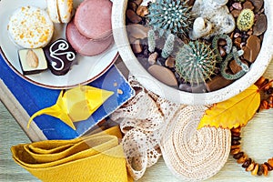 Colorful paper origami, colored macaroons, vintage lace ribbon, amber, flower in a pot, book and napkin on the table. Still life.