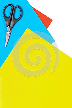 Colorful paper sheets and scissors on white table. Top view, copy space