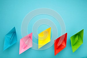 Colorful paper ships on blue background, Leadership and Business competition concepts. Copy space