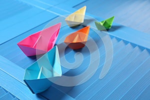 Colorful paper ships on blue wooden background