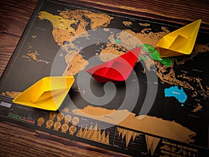 Colorful paper ships on the world map placed on a wooden table