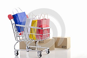 Colorful paper shopping bags in a trolley on white background. Ideas online shopping is a form of electronic commerce that allows