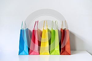 Colorful paper shopping bags on white table and background