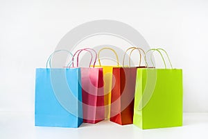 Colorful paper shopping bags on white table and background with copy space