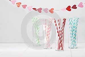 Colorful paper straws with a garland of hearts