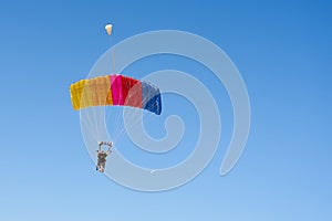 Colorful parachute against a clear blue sky.